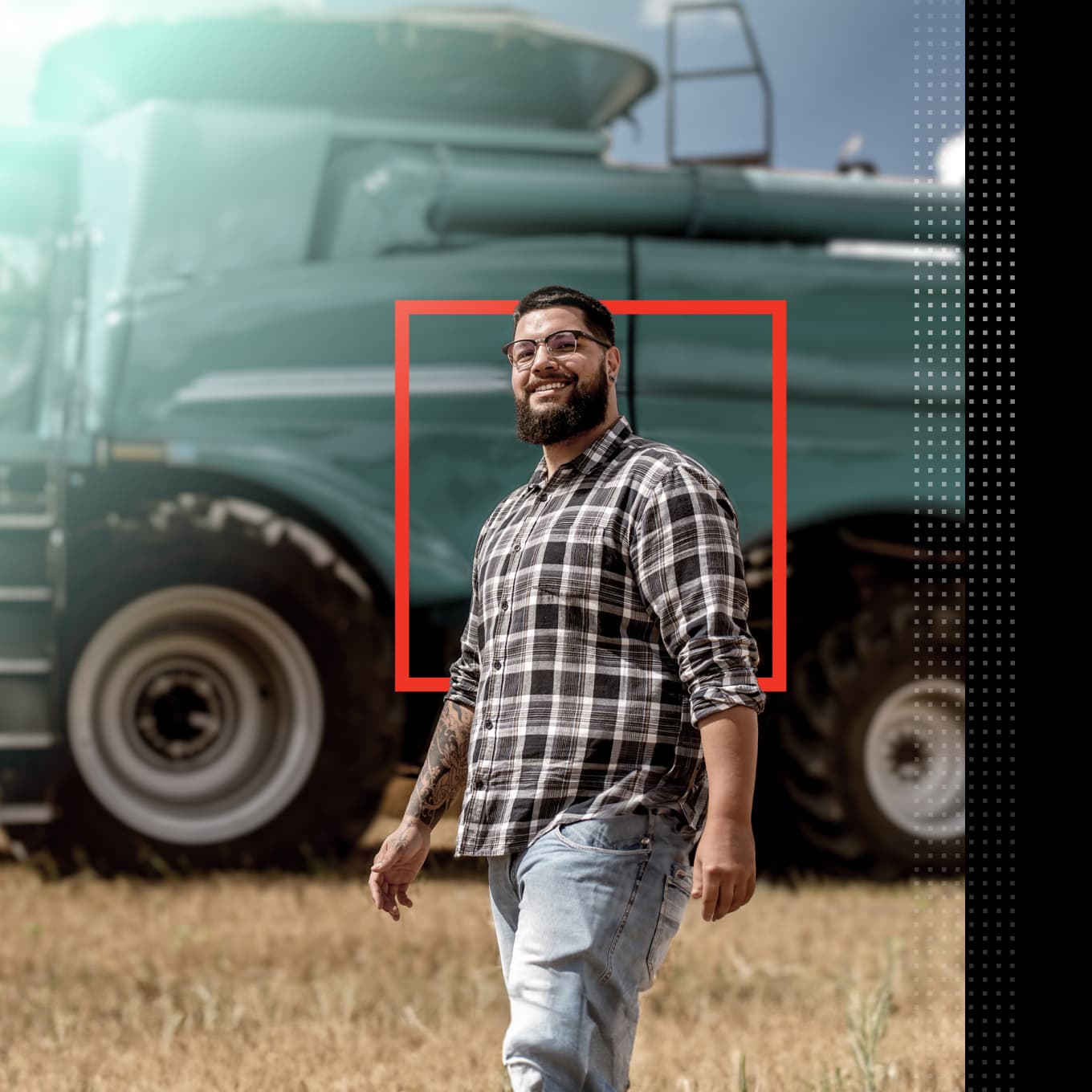 Man standing in a field in front of a large agriculture vehicle